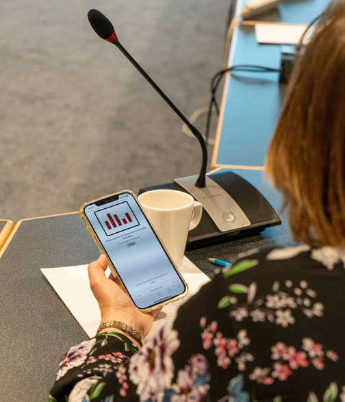 A woman looks at a phone screen showing interactive event polling data