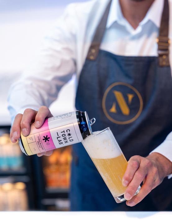 A man in a Nourish branded apron serves up a Cold Town Lab beer