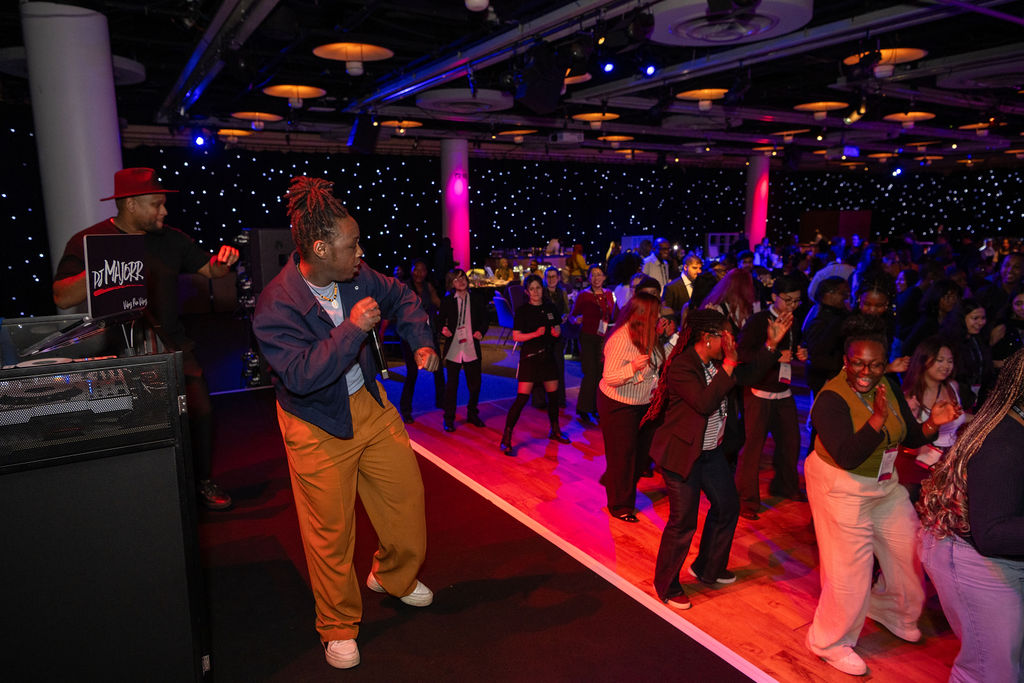 A woman and DJ on stage lead the audience in a dance